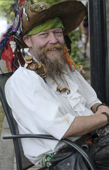 Mantis Quinn shows his commitment to piracy showing off wooden tokens that dangle from his hat.