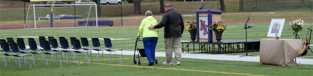 Head NKHS football coach Jeff Weible escorts Dave Snyders mother, Verna Snyder, to the familys seats of honor at the celebration of Snyders life.