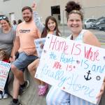 Families waiting for their sailors show off their handmade signs.