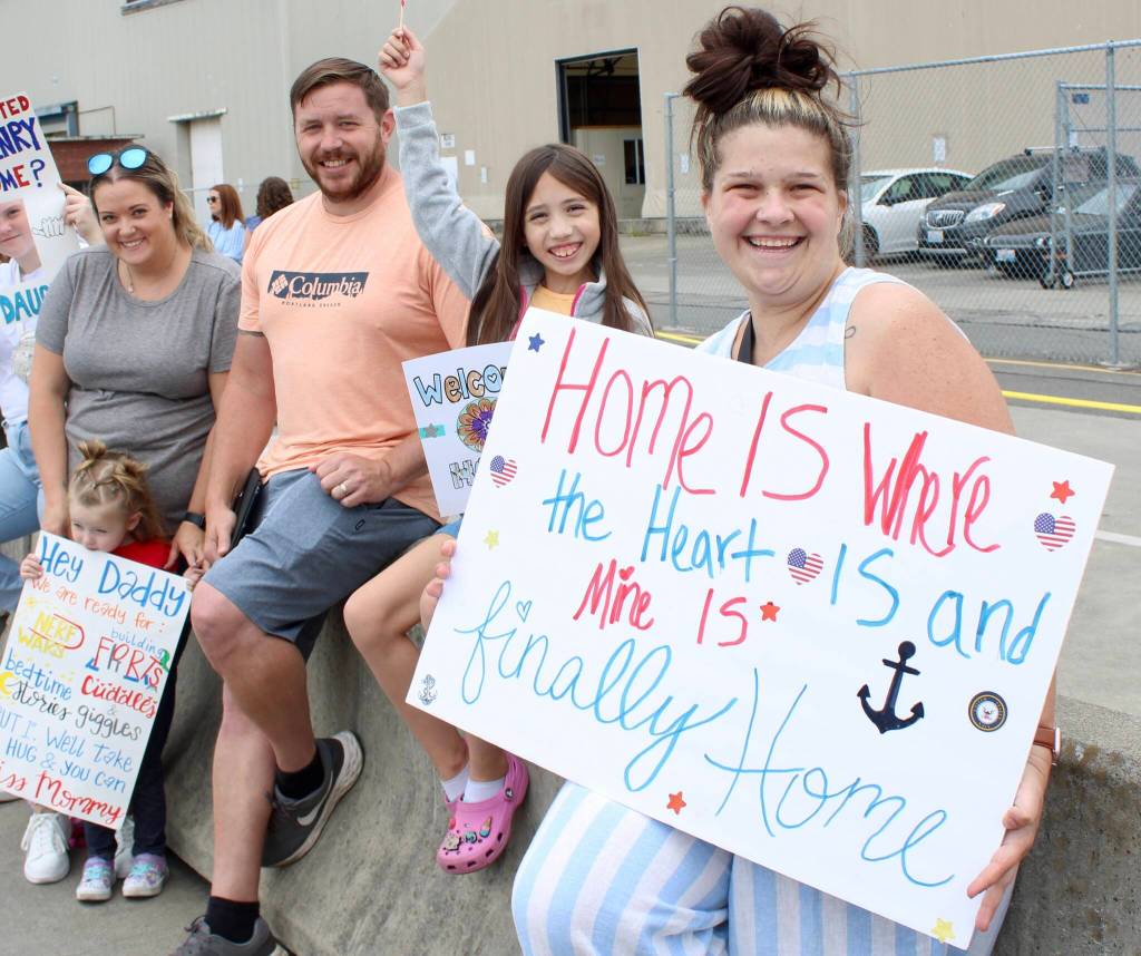 Families waiting for their sailors show off their handmade signs.
