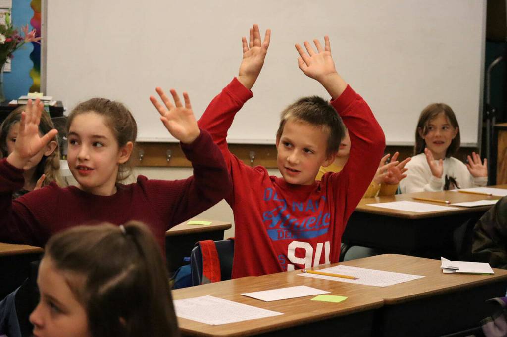 Elementary students wave both hands in the air to celebrate the first day of school.
