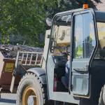 Darren Sykes uses a heavy-duty forklift attachment to dump debris from the renovation into a larger receptacle.