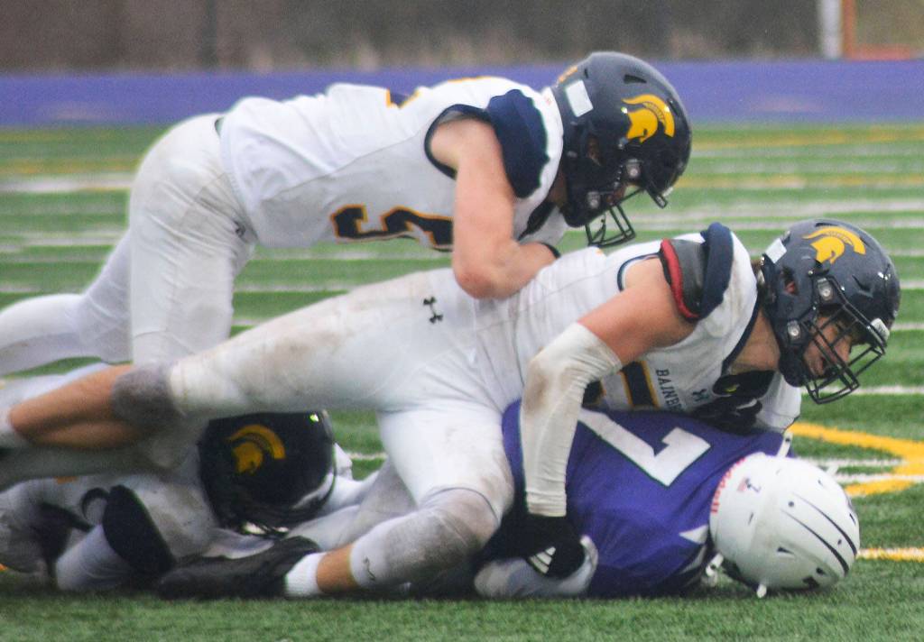 Three Spartans crunch an Anacortes receiver during a gang tackle at the game.