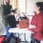 Merlaine Cook watches Joey Antworth repair the turntable on her stereo.