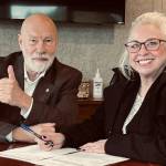 SK Helpline executive director Jennifer Hardison closes the deal alongside the organizations past president Neal Perrine.