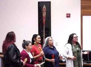 BKAT courtesy photo
Suquamish tribal members perform a traditional song during the Jan. 7 Poulsbo City Council meeting. The ceremonial Suquamish paddle is on display in the background.